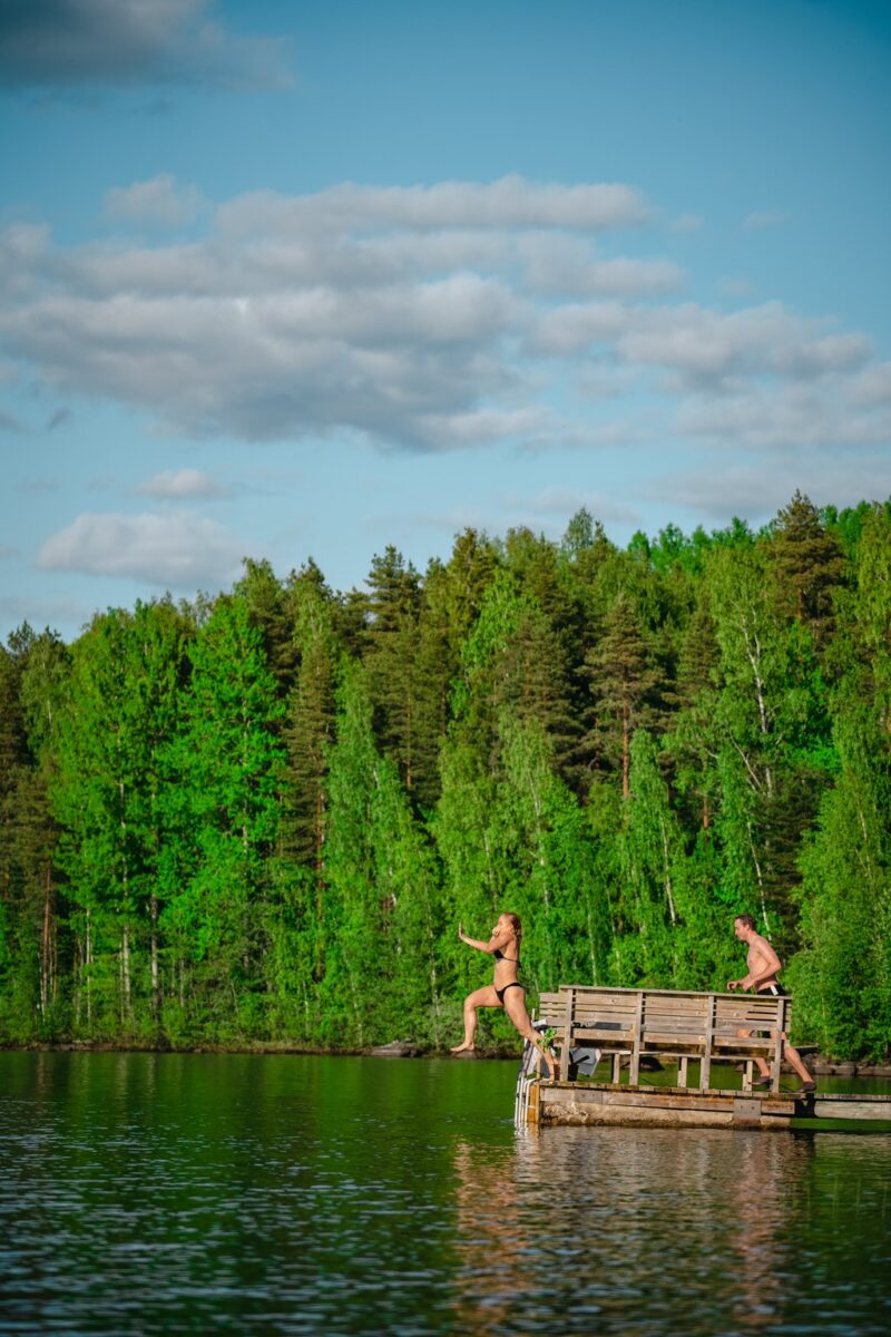 Man and woman diving into a lake in Finland.