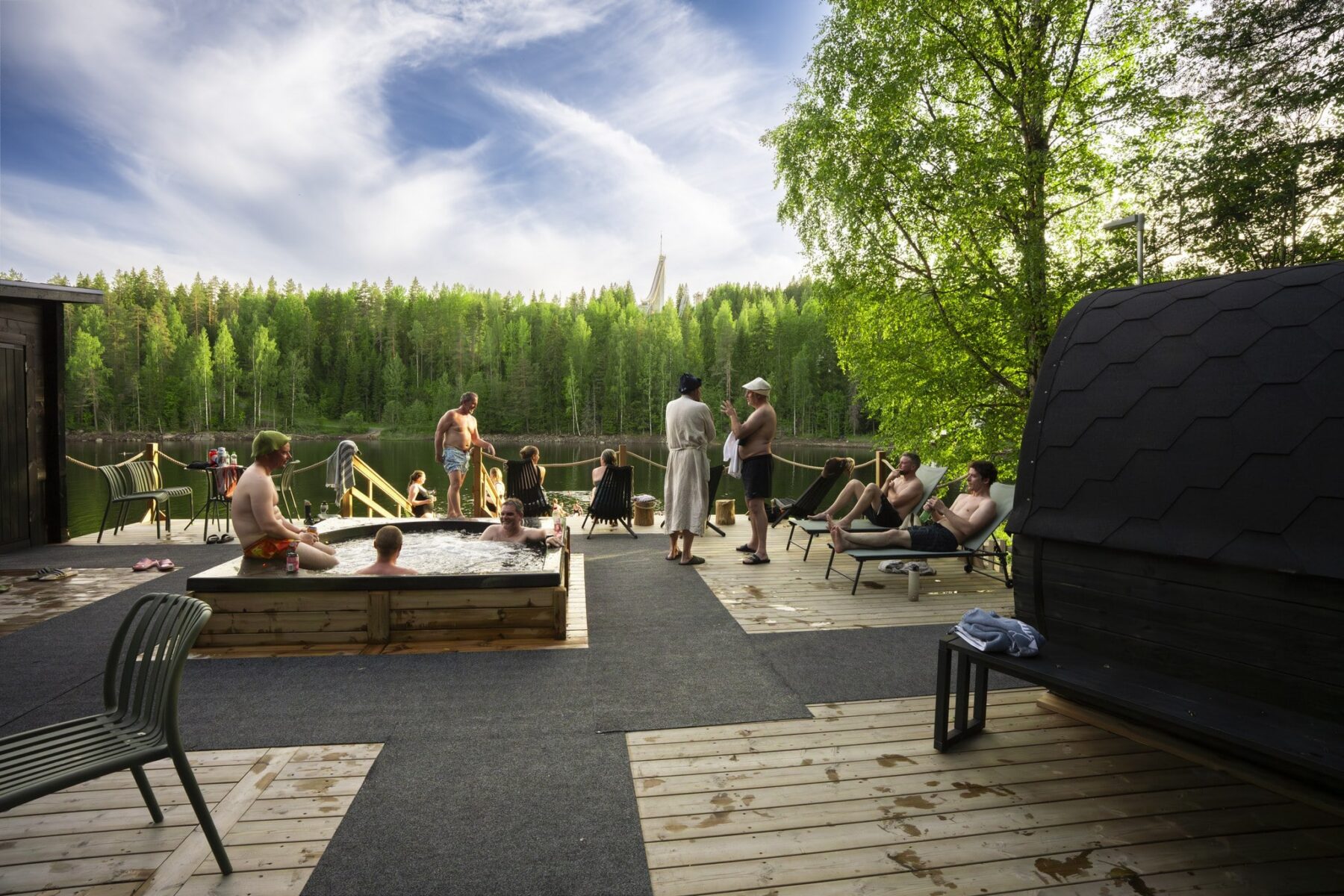 People in front of the lake in hot tubs and saunas at the World Sauna Forum pre-tour at Sauna Lampila in Jyväskylä